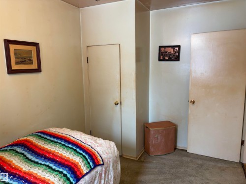 This room features a neutral wall color, carpeted flooring, and two white doors with brass-toned doorknobs - 10916 151 Street, Edmonton, AB - Indoor Photo Showing Bedroom