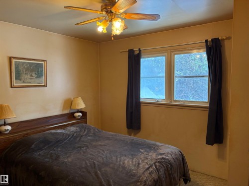 This room features a ceiling fan with integrated lighting, a window with curtains, and wall-to-wall carpeting - 10916 151 Street, Edmonton, AB - Indoor Photo Showing Bedroom