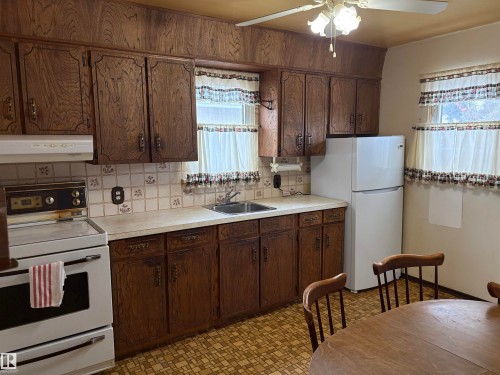 The kitchen features wood cabinetry, a white refrigerator, and a white electric range - 10916 151 Street, Edmonton, AB - Indoor Photo Showing Kitchen