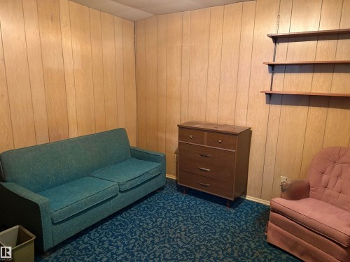 This room features wood paneling on the walls and carpeted flooring with a patterned design - 10916 151 Street, Edmonton, AB - Indoor
