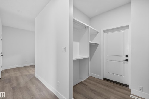 This interior space features light wood-look flooring, white walls, and a built-in storage area with shelving and a hanging rod - 190 Elliott Wynd, Fort Saskatchewan, AB - Indoor