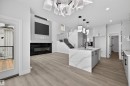 The property features an open-concept living area with light-colored flooring, a modern kitchen island with a white countertop and dark base cabinets, and a contemporary light fixture - 190 Elliott Wynd, Fort Saskatchewan, AB  - Indoor 