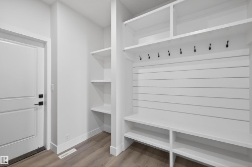 Well-appointed mudroom featuring built-in shelving, coat hooks, and a bench with cubby storage, all in a clean white finish - 190 Elliott Wynd, Fort Saskatchewan, AB - Indoor With Storage