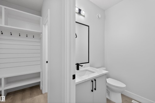 This property features a built-in storage unit with shelving and coat hooks, alongside a bathroom with a modern vanity, a rectangular sink, and a toilet - 190 Elliott Wynd, Fort Saskatchewan, AB - Indoor Photo Showing Bathroom