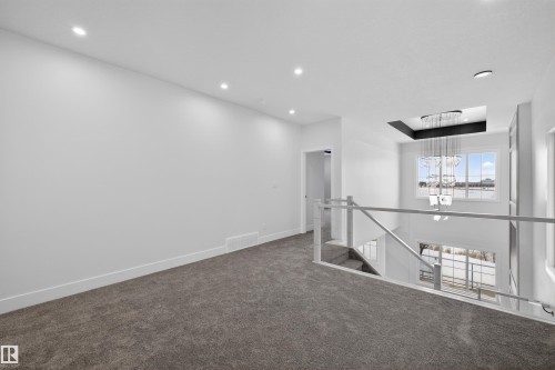 Carpeted landing area featuring recessed lighting, a modern chandelier, and a window providing natural light - 190 Elliott Wynd, Fort Saskatchewan, AB - Indoor Photo Showing Other Room