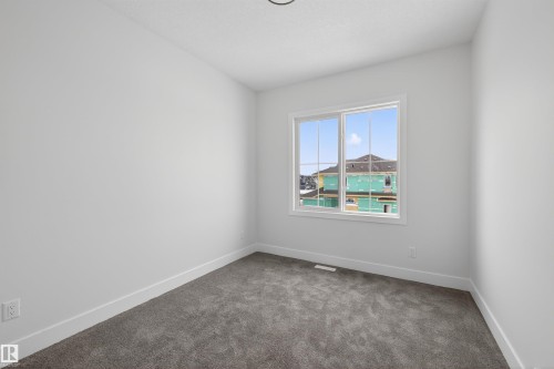 This room features clean white walls, a large window, and gray carpet - 190 Elliott Wynd, Fort Saskatchewan, AB - Indoor Photo Showing Other Room