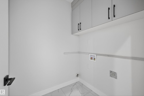 Utility area with overhead cabinetry featuring black handles and a tiled floor - 190 Elliott Wynd, Fort Saskatchewan, AB - Indoor