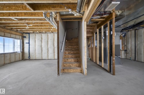 The property features an unfinished area with concrete flooring, exposed wooden ceiling joists, and a window providing natural light - 190 Elliott Wynd, Fort Saskatchewan, AB - Indoor Photo Showing Basement
