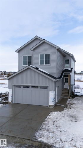 The property features gray siding, a two-car garage with a gray door, and an entryway with a white door and steps - 190 Elliott Wynd, Fort Saskatchewan, AB - Outdoor