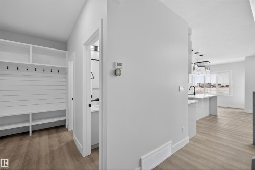 This property features an entryway with built-in shelving, storage cubbies, and coat hooks, with a bathroom visible beyond a white door - 190 Elliott Wynd, Fort Saskatchewan, AB - Indoor Photo Showing Other Room
