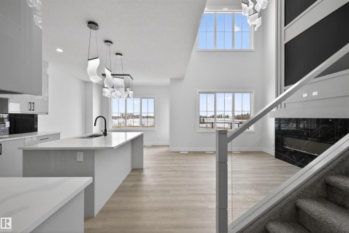 The open concept living area features a kitchen island with a sink, light-toned flooring, and large windows providing natural light - 190 Elliott Wynd, Fort Saskatchewan, AB - Indoor Photo Showing Kitchen With Upgraded Kitchen