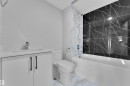 Bathroom featuring a toilet, bathtub with black marble-style wall tiles, and a vanity with a white countertop and chrome faucet - 5118 17A Ave, Edmonton, AB  - Indoor Photo Showing Bathroom 