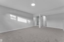 Spacious room featuring carpeting, light-colored walls, and an overhead light fixture, with a partial view of a toilet and a door opening into an additional area - 5118 17A Ave, Edmonton, AB  - Indoor Photo Showing Other Room 