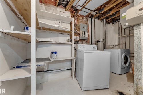 The utility area features a top-loading washing machine and a front-loading dryer, alongside built-in shelving for storage - 5118 17A Ave, Edmonton, AB - Indoor Photo Showing Laundry Room