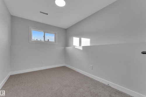 This inviting room features soft gray walls, a window providing natural light, and plush carpeting for comfort - 5118 17A Ave, Edmonton, AB - Indoor Photo Showing Other Room