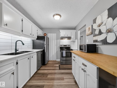 The kitchen features white cabinetry, a dual basin sink with a matte black faucet, and a subway tile backsplash - 165 2703 79 Street, Edmonton, AB - Indoor Photo Showing Kitchen With Double Sink