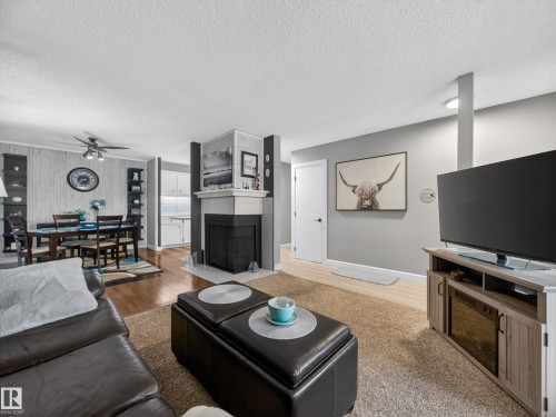 The living area features a fireplace with a white mantel, hardwood flooring, and a ceiling fan - 165 2703 79 Street, Edmonton, AB - Indoor Photo Showing Living Room