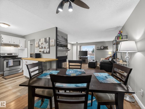 The property features an open-concept living area with light-colored flooring, a kitchen with white cabinetry and stainless steel appliances, and a living room with a large window - 165 2703 79 Street, Edmonton, AB - Indoor