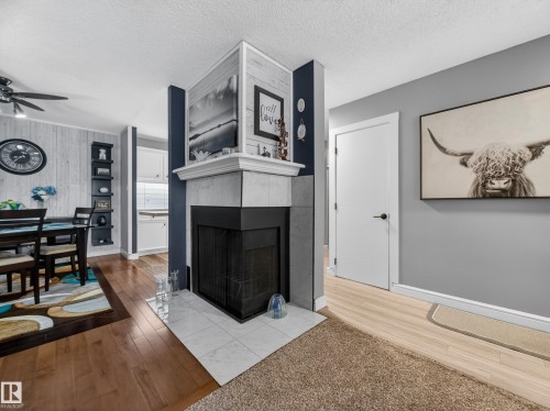 Living room featuring a fireplace with a tiled hearth and mantel, hardwood flooring, and a ceiling fan - 165 2703 79 Street, Edmonton, AB - Indoor Photo Showing Other Room With Fireplace