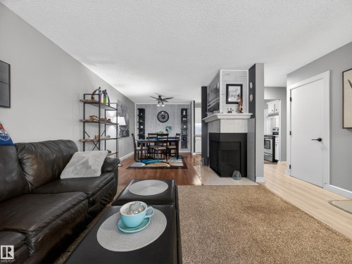 The living area features a fireplace with a white mantel, hardwood flooring, and a ceiling fan - 165 2703 79 Street, Edmonton, AB - Indoor Photo Showing Living Room With Fireplace