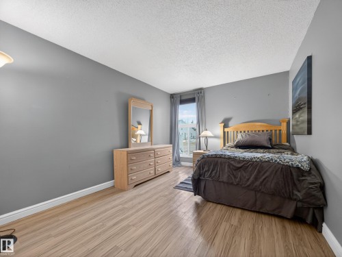 This room features light wood-look flooring, a window with grey curtains, and walls painted in a neutral grey tone - 165 2703 79 Street, Edmonton, AB - Indoor Photo Showing Bedroom