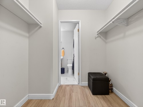 The property features a walk-in closet with built-in shelving, hanging rods, and wood-look flooring - 165 2703 79 Street, Edmonton, AB - Indoor With Storage