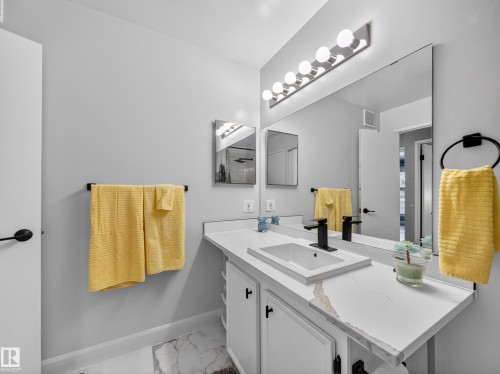 Bathroom featuring a vanity with a rectangular sink, a black faucet, and a large wall-mounted mirror - 165 2703 79 Street, Edmonton, AB - Indoor Photo Showing Bathroom