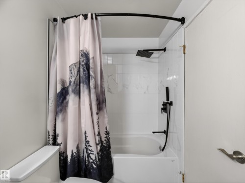Bathroom featuring a white bathtub, white tiled walls, and matte black shower fixtures - 165 2703 79 Street, Edmonton, AB - Indoor Photo Showing Bathroom
