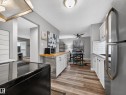 The kitchen features wood-look flooring, white cabinetry, a wood countertop on the island, and a stainless steel refrigerator - 165 2703 79 Street, Edmonton, AB  - Indoor Photo Showing Kitchen 