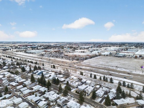 Aerial view showcasing the surrounding neighborhood, featuring residential properties with snow-covered rooftops, a highway with vehicular traffic, and commercial buildings - 165 2703 79 Street, Edmonton, AB - Outdoor With View