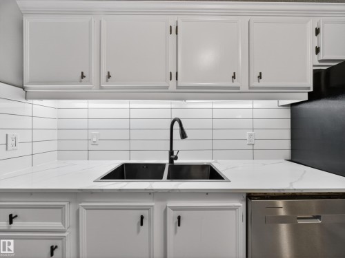 Kitchen featuring white cabinetry, a black dual basin sink with a matte black faucet, and white subway tile backsplash - 165 2703 79 Street, Edmonton, AB - Indoor Photo Showing Kitchen With Double Sink