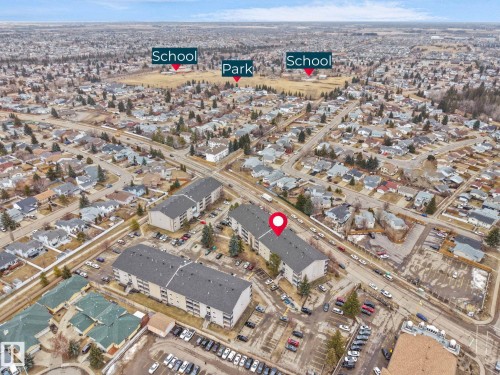 Aerial view showcasing the property's proximity to a park and schools, alongside residential streets and parking areas - 214 2620 Mill Woods Road E, Edmonton, AB - Outdoor With View