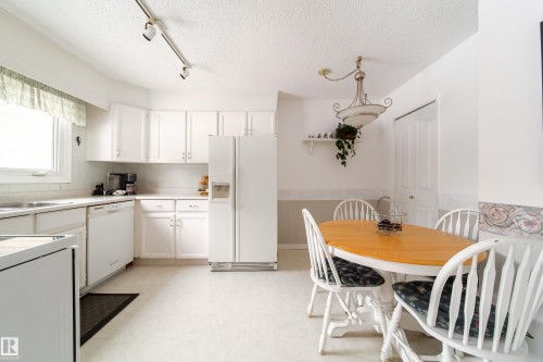 The kitchen features white cabinetry and appliances, track lighting, and a window with a valance - 11 Granada Place, St. Albert, AB - Indoor