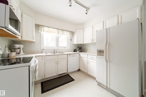 Kitchen with white cabinetry, a window above the sink, and track lighting - 11 Granada Place, St. Albert, AB - Indoor Photo Showing Kitchen With Double Sink