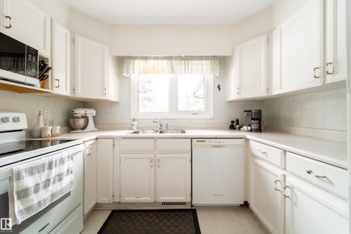 Kitchen with white cabinetry, a window above the sink, white countertops, and white appliances - 11 Granada Place, St. Albert, AB - Indoor Photo Showing Kitchen With Double Sink