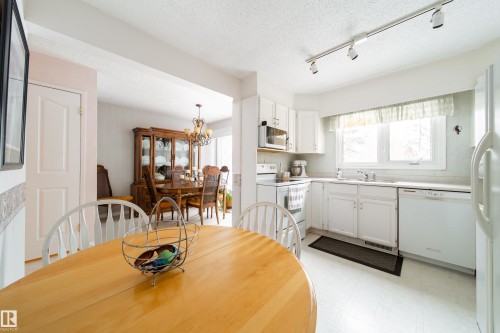 The property features a kitchen with white cabinetry, a sink under a window, and a white refrigerator - 11 Granada Place, St. Albert, AB - Indoor