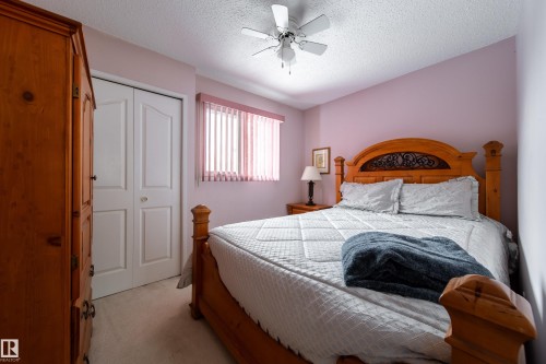 This room features a ceiling fan, a window with blinds, and a built-in closet with bi-fold doors - 11 Granada Place, St. Albert, AB - Indoor Photo Showing Bedroom