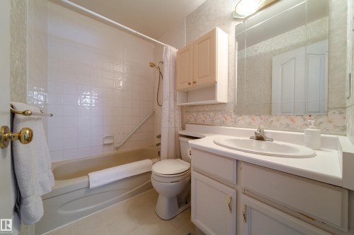 The bathroom features a bathtub with a tiled surround, a toilet, and a vanity with a sink and cabinets - 11 Granada Place, St. Albert, AB - Indoor Photo Showing Bathroom