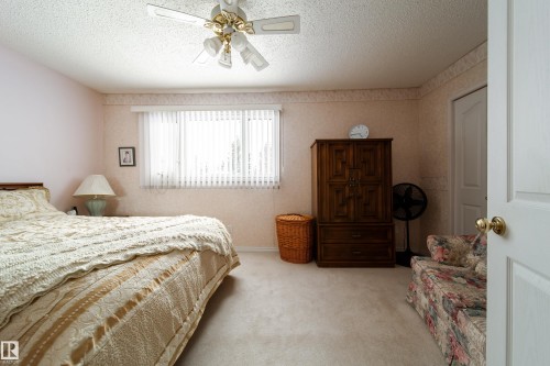 This spacious room features carpeted flooring, a ceiling fan, and a window with blinds providing natural light - 11 Granada Place, St. Albert, AB - Indoor Photo Showing Bedroom
