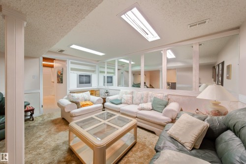 This recreation room features wall-to-wall carpeting and built-in shelving - 11 Granada Place, St. Albert, AB - Indoor Photo Showing Living Room