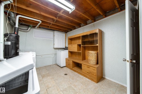 Utility area featuring tile flooring, exposed wooden ceiling beams, and a fluorescent light fixture - 11 Granada Place, St. Albert, AB - Indoor Photo Showing Basement