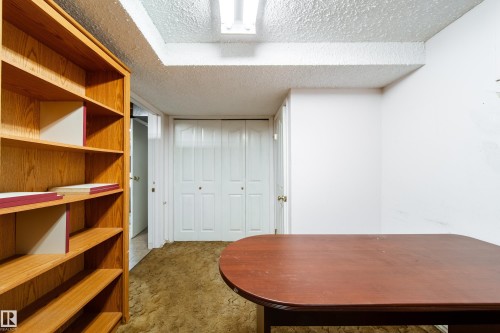 This room features a built-in wooden bookshelf, a white bi-fold closet, and a white door with a brass doorknob - 11 Granada Place, St. Albert, AB - Indoor Photo Showing Other Room