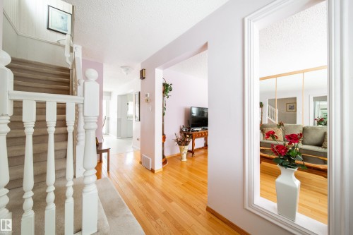The entry hall features hardwood flooring and a carpeted staircase with white balusters - 11 Granada Place, St. Albert, AB - Indoor Photo Showing Other Room