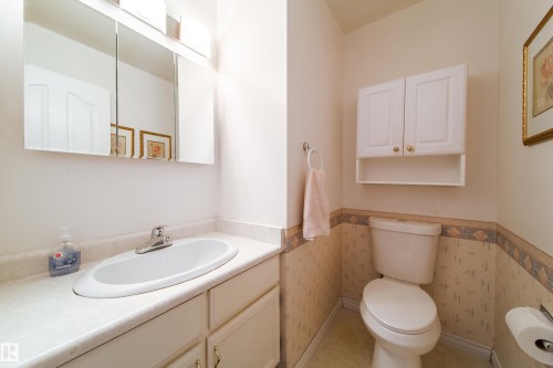 The bathroom features a vanity with a white sink and built-in storage, a wall-mounted medicine cabinet with a mirrored front, and a white toilet - 11 Granada Place, St. Albert, AB - Indoor Photo Showing Bathroom