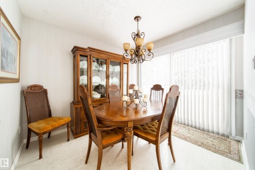 Dining area featuring a decorative chandelier and large windows with vertical blinds - 11 Granada Place, St. Albert, AB - Indoor Photo Showing Dining Room