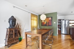 Dining area with hardwood floors, a contemporary chandelier, and a feature wall - 