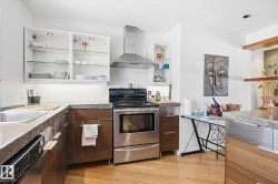 The kitchen features stainless steel appliances, including an oven with an overhead range hood and a dishwasher - 
