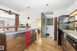 The kitchen features hardwood floors, a stone countertop, and pendant lighting - 