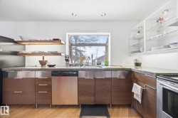 Kitchen featuring wood flooring, a window, stainless steel appliances, and wood cabinetry with stainless steel drawer pulls - 