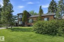 The property features a brick exterior, a bay window, and a well-maintained lawn with mature trees and shrubs/  This is a summer picture using AI - 11026 110 Avenue, Edmonton, AB  - Outdoor 